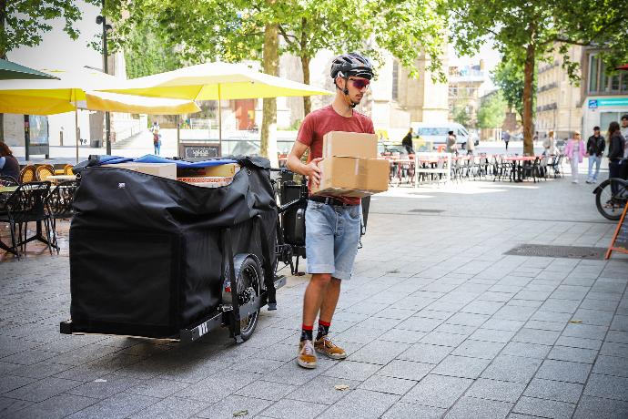 Coursier qui livre des colis transportés à bord d'une Runner avec Megabag