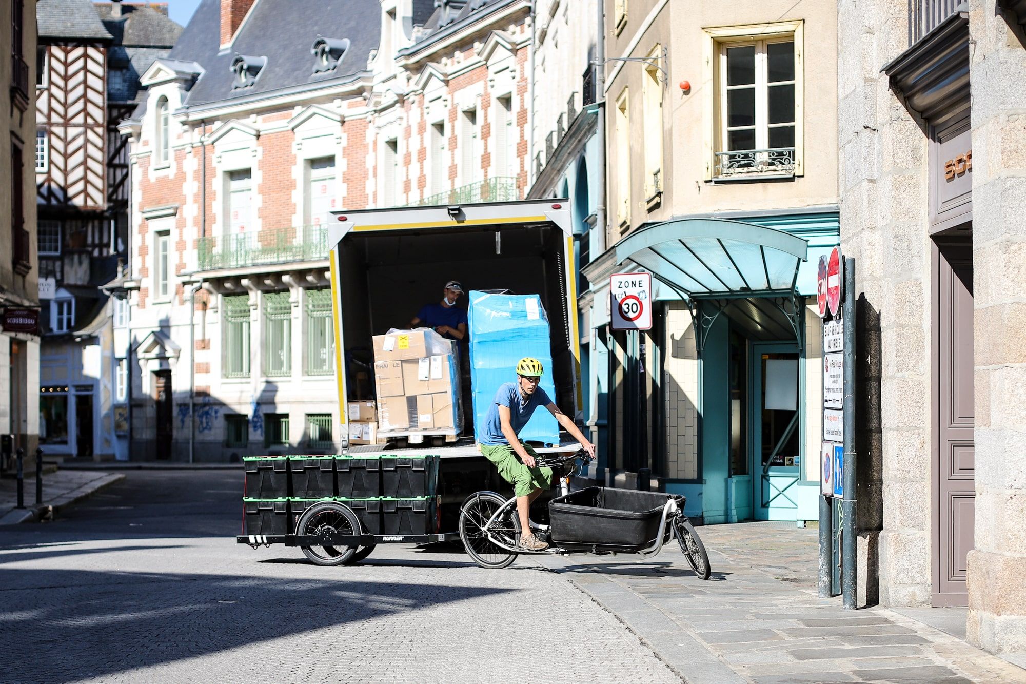 Cyclist on a cargo bike and a trailer with eight black boxes on it