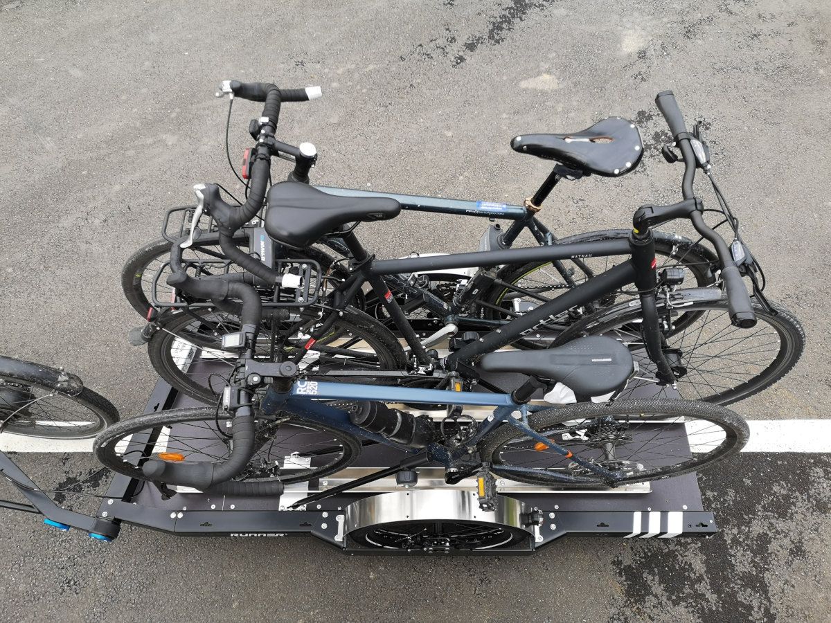 Bike transport Trailer attached to a bike with 3 bikes on it, two racing bikes and one urban bike
