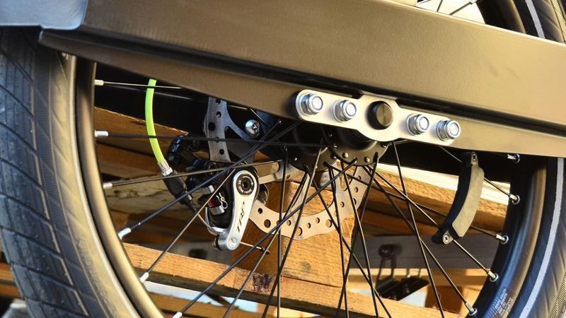 Wheel of a bike trailer with TRP disc brakes and a yellow cable, the wheel is fixed with four bolts and an axle