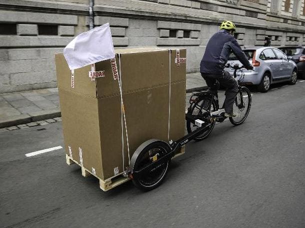 Courier on a bike towing the BicyLift bike trailer with a pallet on it