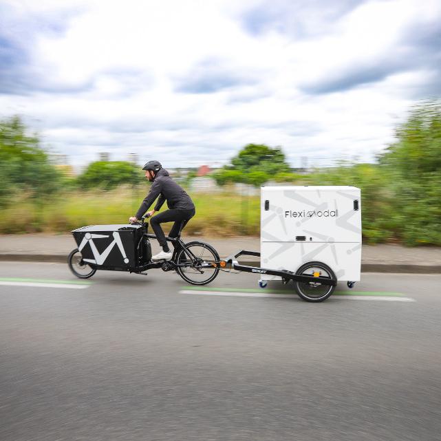 Person on a bike pulling the BicyLift bike trailer and the Parcel Container