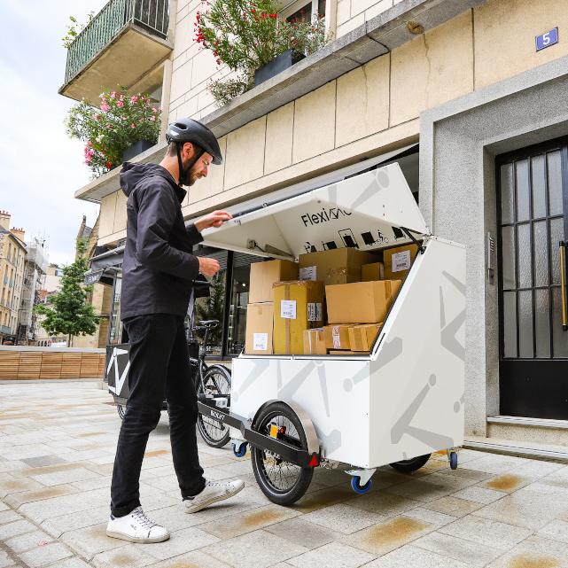 Livreur ouvrant le conteneur colis pour effectuer une livraison en ville
