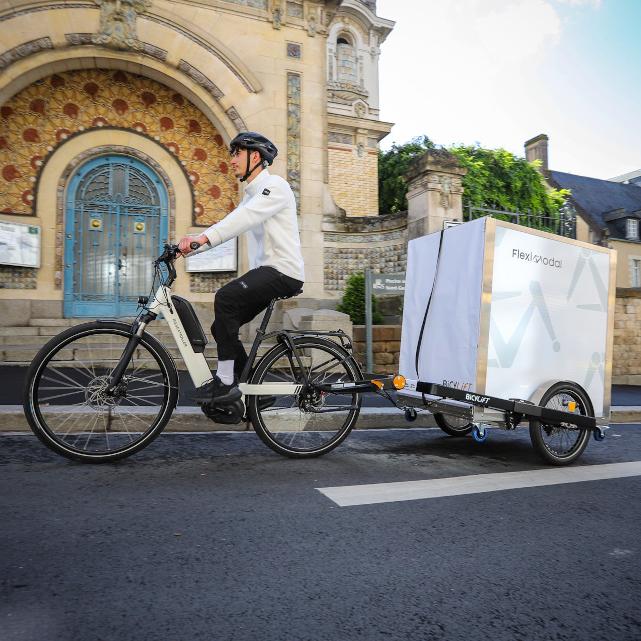 Livreur à vélo tractant une Bicylift et un rack à bacs