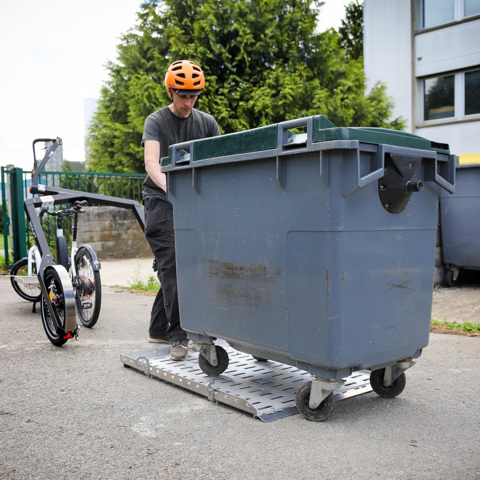 Person loading a trash bin onto the Flatbed