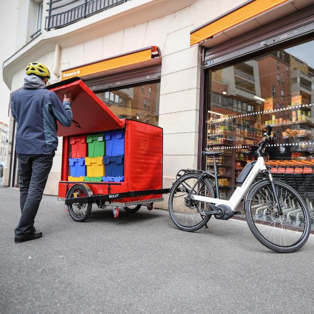 Courier opening a XL9 isothermal container with colorful standard boxes inside it, a Riese &amp;amp; Müller bike infront