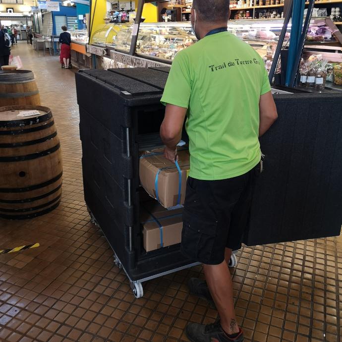 Livreur poussant un conteneur ROLL O'CITY dans les halles