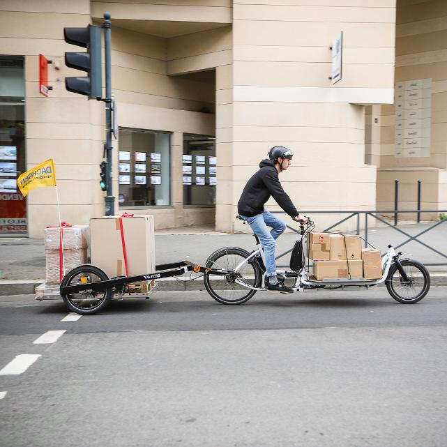 Bike courier on a biicycle pulling a trailer with heavy load on it