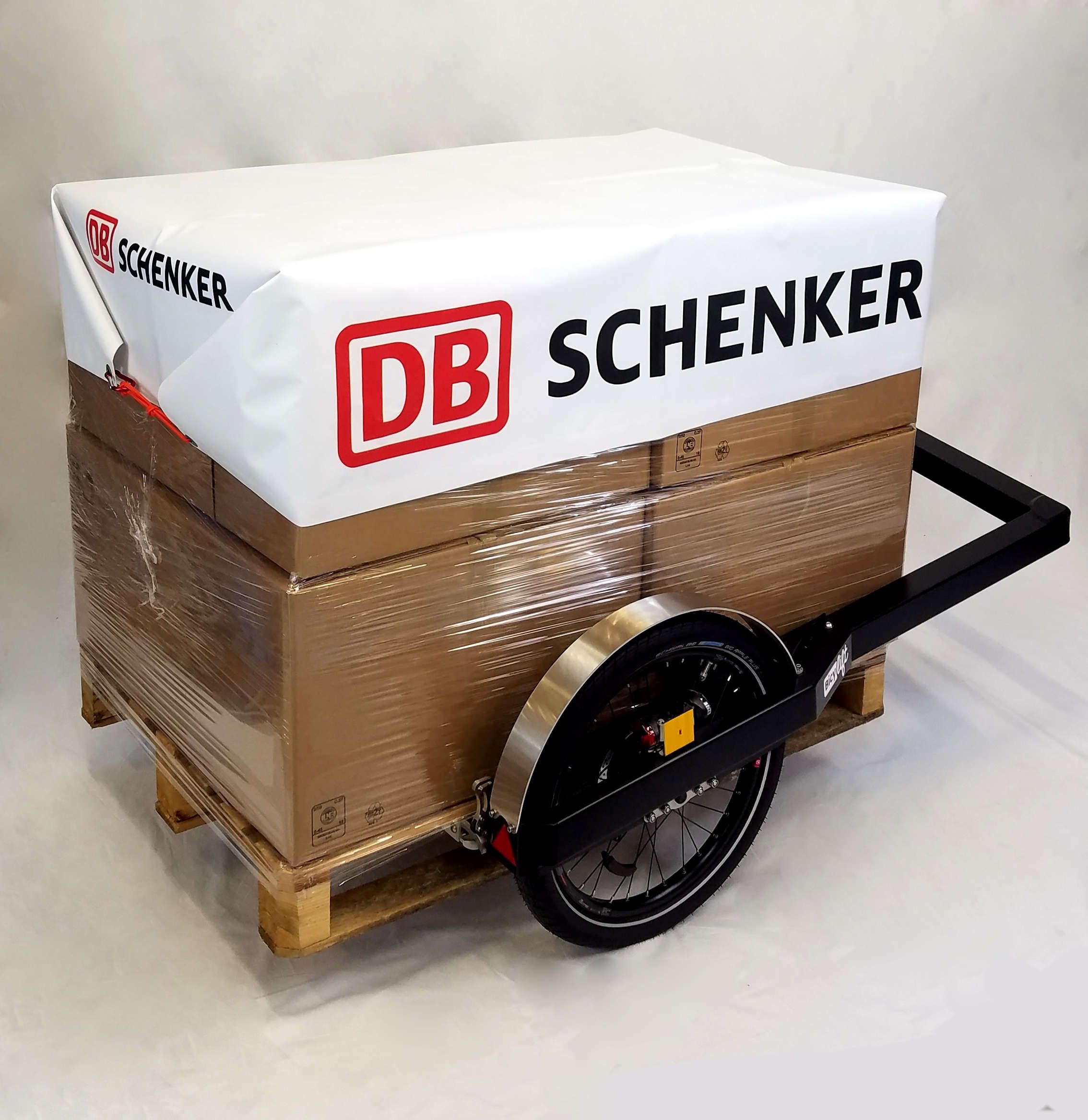 BicyLift bike trailer with a pallet and cardboard boxes packaged in transparent plastic foil with a white tarp on it