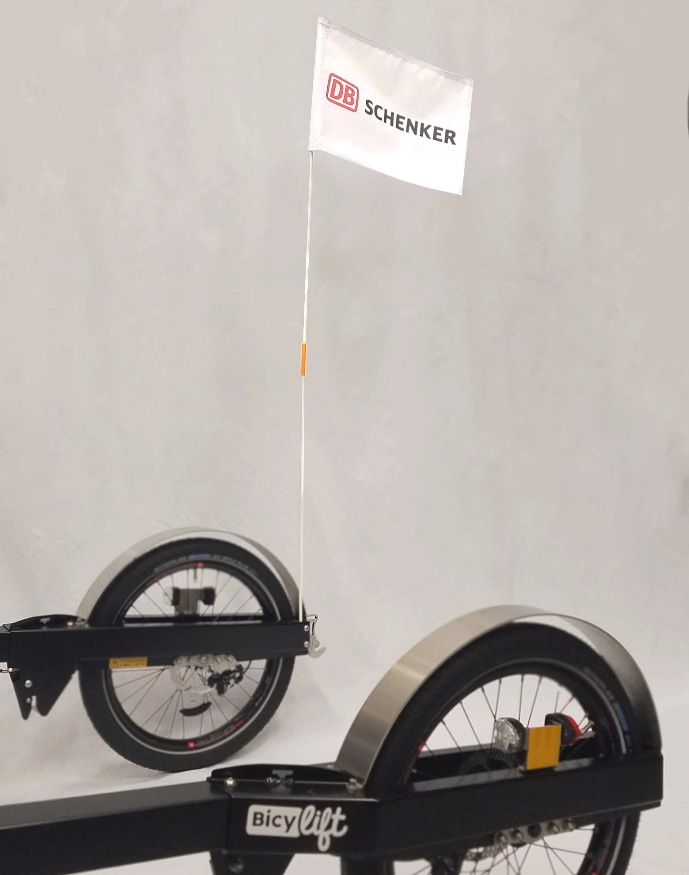 Part of the frame of the BicyLift bike trailer two wheel with mudguards and a front and back light, a signage flag is attached at the back of the trailer